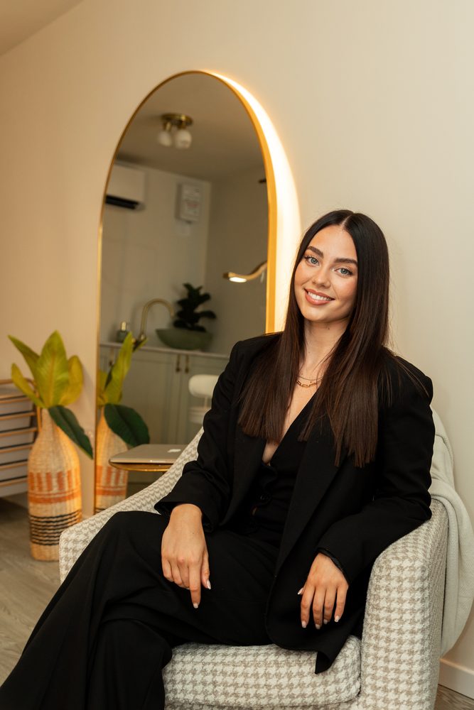 Kenadi, founder of Arch Cosmetics, sitting in her studio